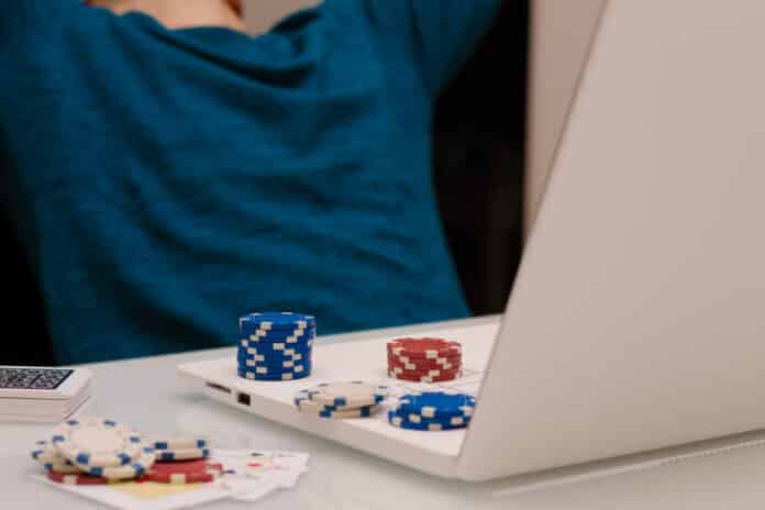 Gamer man playing with his laptop from home to casino games, poker, blackjack, roulette. Concept of online gambling, win money, sports bet, chance, succeed, fortune, addiction